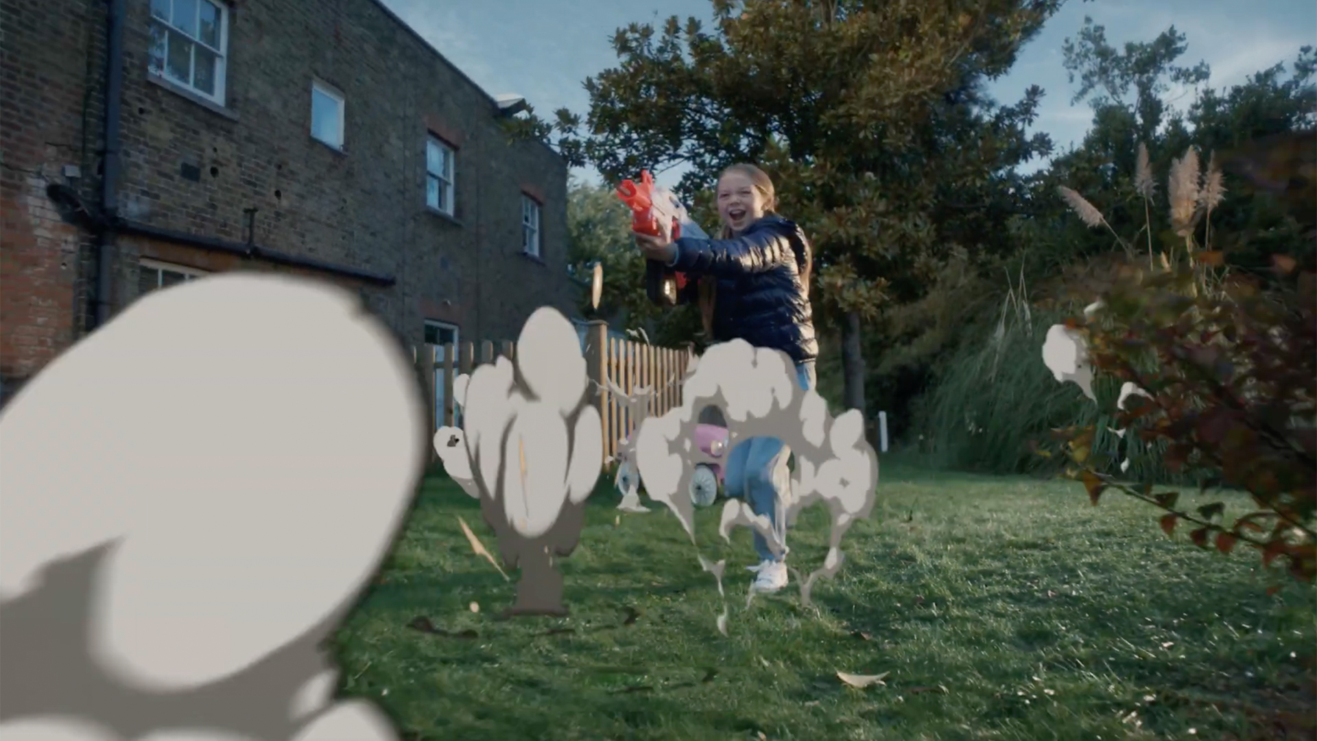 Exterior shot of a back garden with a girl around 10 years old playing with a super soaker.